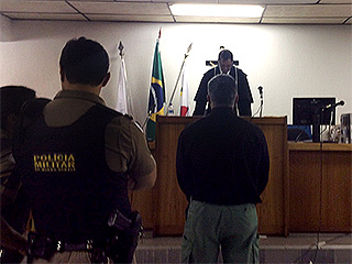 O réu se posiciona à frente do juiz para ouvir a sentença