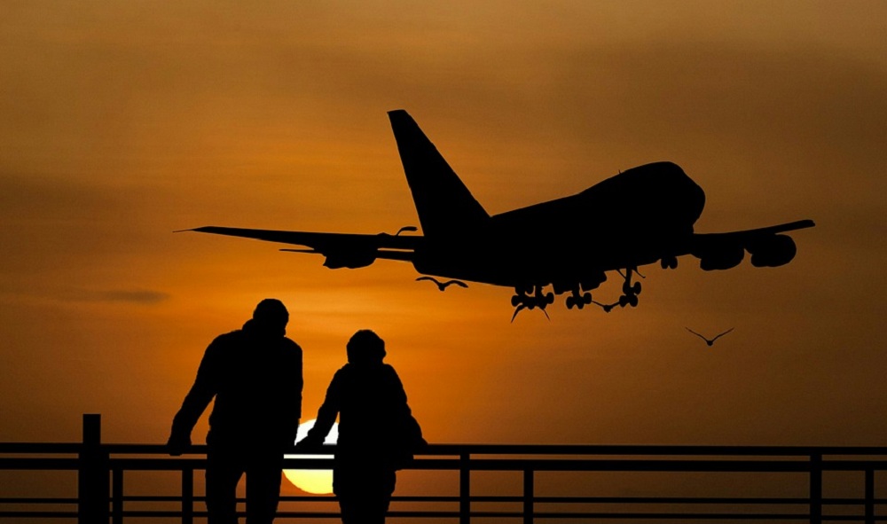 Um homem e uma mulher com avião decolando ao fundo