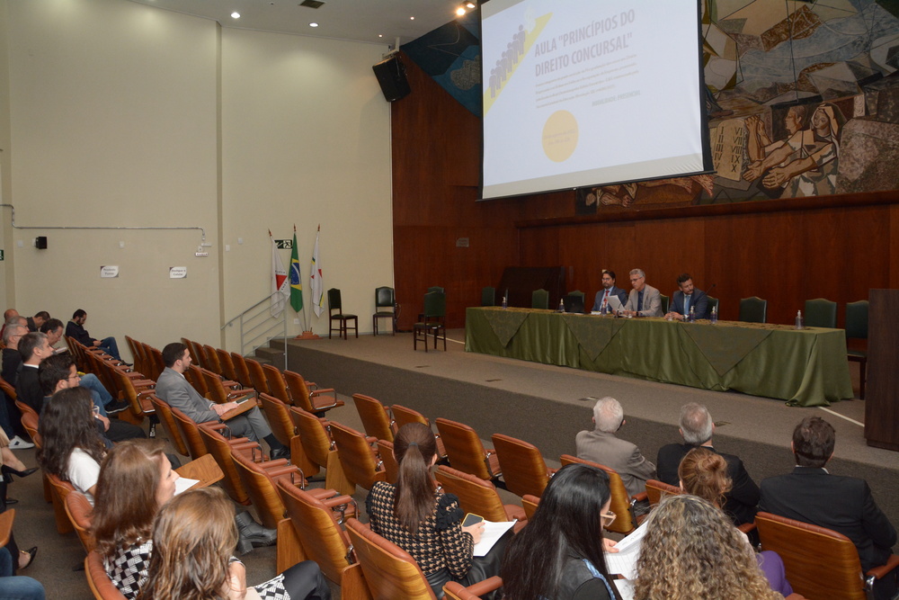 Vista de auditório, com plateia e mesa de honra com debatedores
