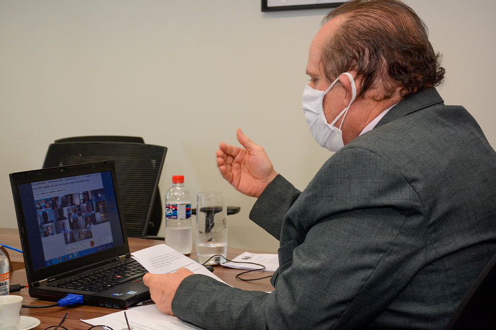 Magistrado de máscara diante de notebook ligado participa de reunião virtual
