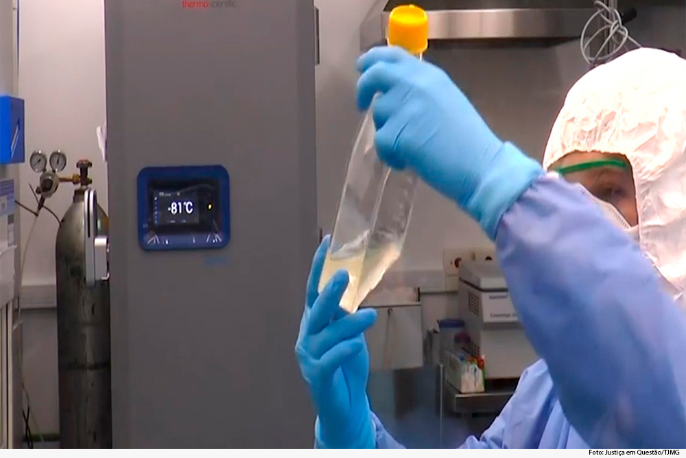 Cientista vestido com equipamentos de proteção analisa amostra em um recipiente