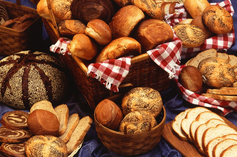 Pães, bolos e biscoitos em cestas de vime sobre mesa coberta com toalha