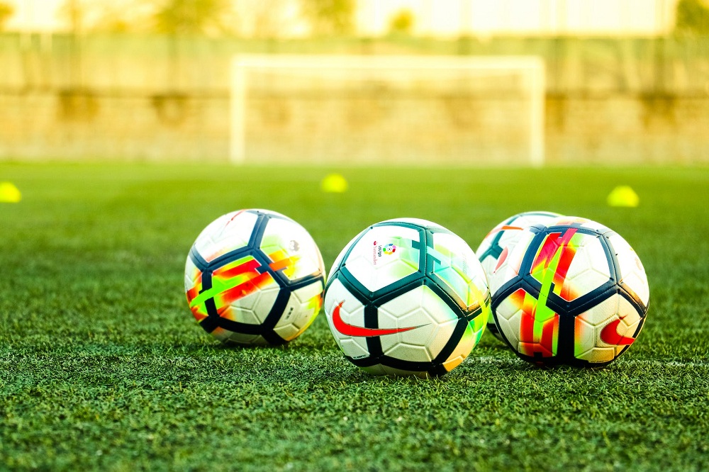 Três bolas de futebol em gramado