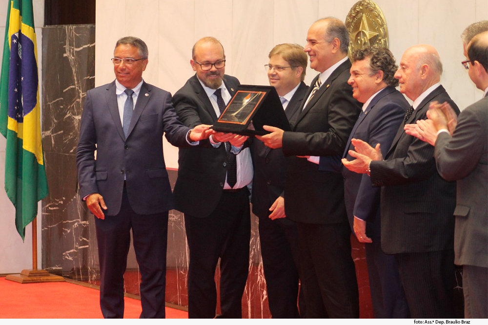 Imagem mostra o desembargador Jair Varão exibindo placa alusiva ao seu título de cidadão honorário do Estado de Minas Gerais