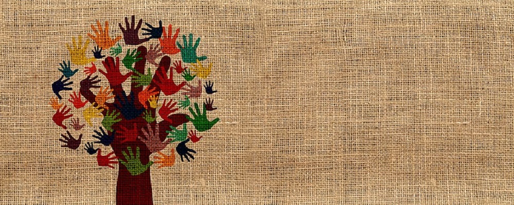 Tecido bordado mostra árvore cuja copa é composta de mãos coloridas