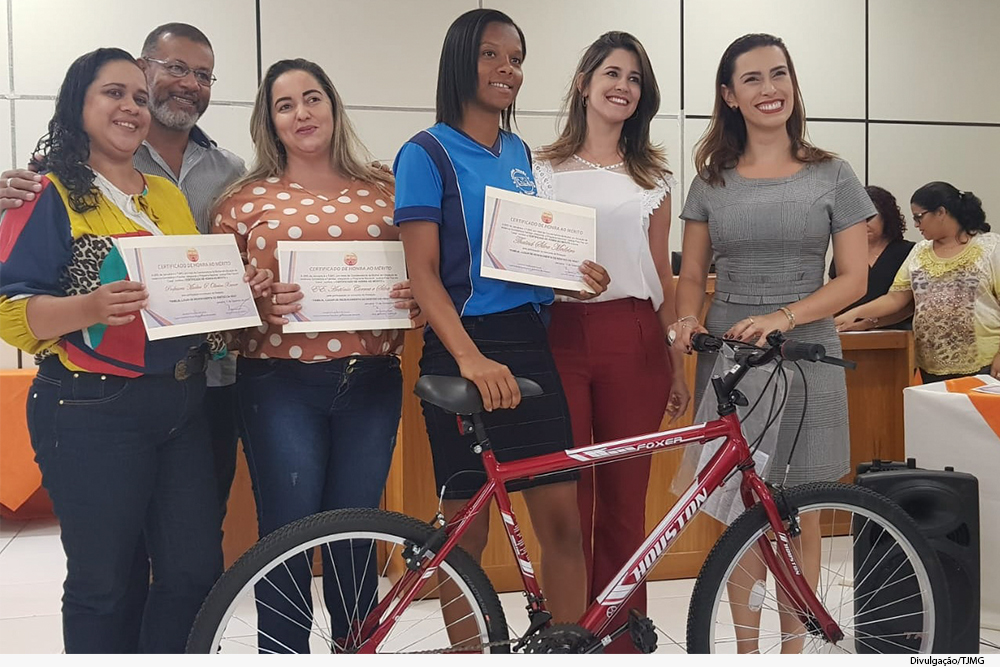 Pessoas sorridentes de pé seguram bicicleta