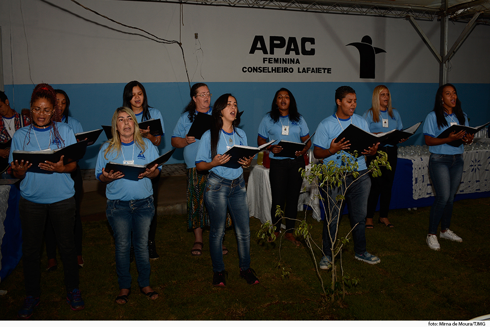 Mulheres de uniforme cantam em solenidade na Apac