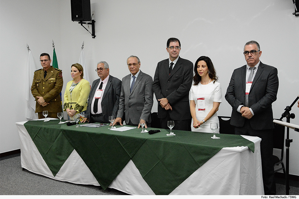 Mesa de honra com autoridades de pÃ© em evento