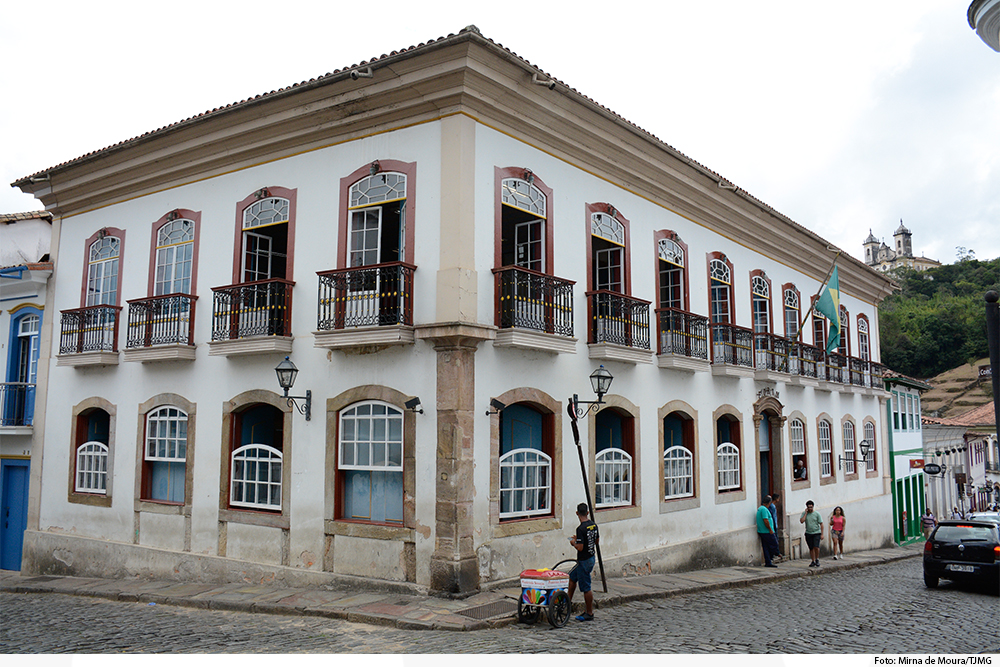 Prédio colonial com vendedor de picolé e pessoas na calçada