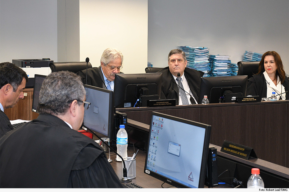 Presidente de sessão, de perfil, fala a colegas em sessão