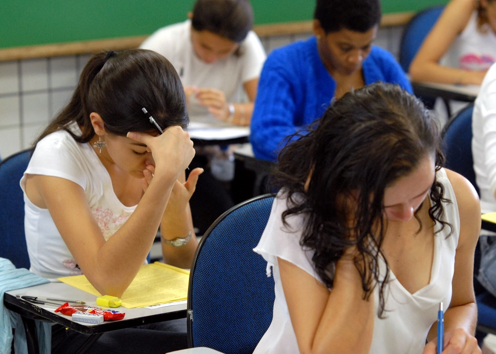 Estudantes, em sala de aula, fazendo prova
