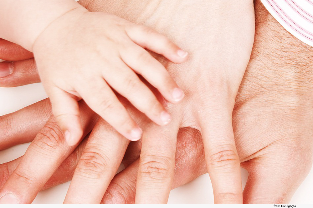 Mãos de adultos e de bebê sobrepostas