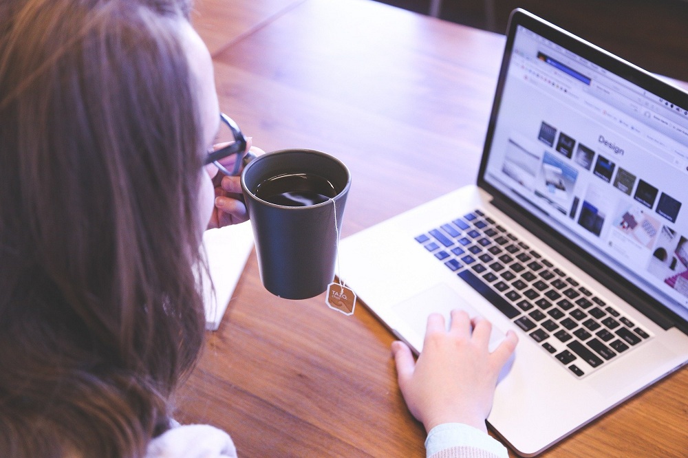 Mulher jovem diante do computador com caneca