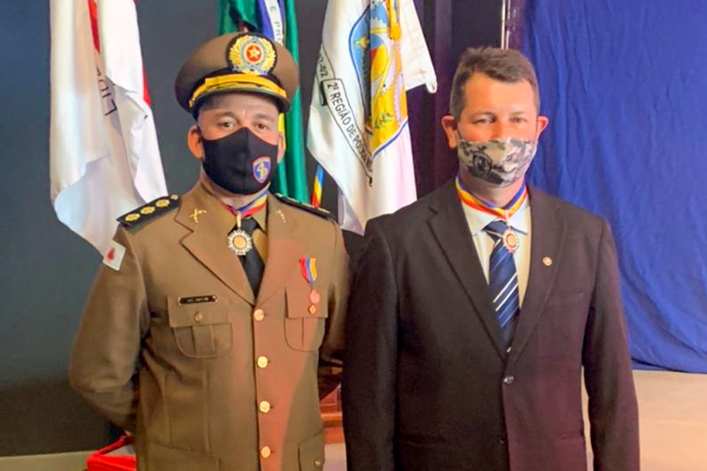 Juiz e militar em frente a bandeiras em solenidade