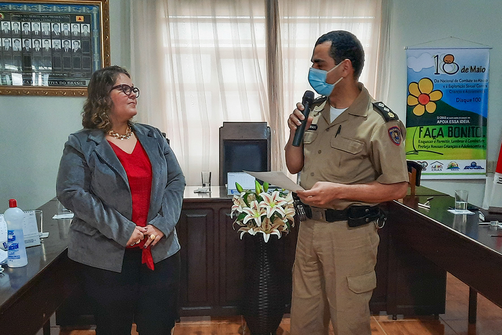 Juíza e policial militar, de pé, em evento na Câmara de Vereadores