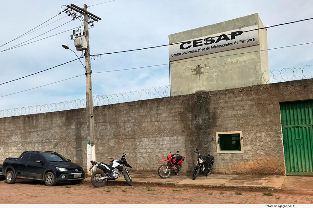 Fachada do centro socioeducativo de Pirapora, com carro e motos estacionados em frente ao local