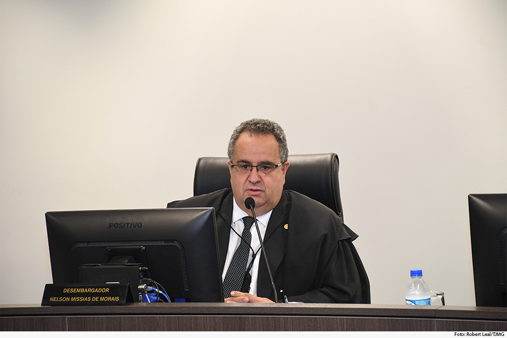 Homem de terno sentado em frente a microfone