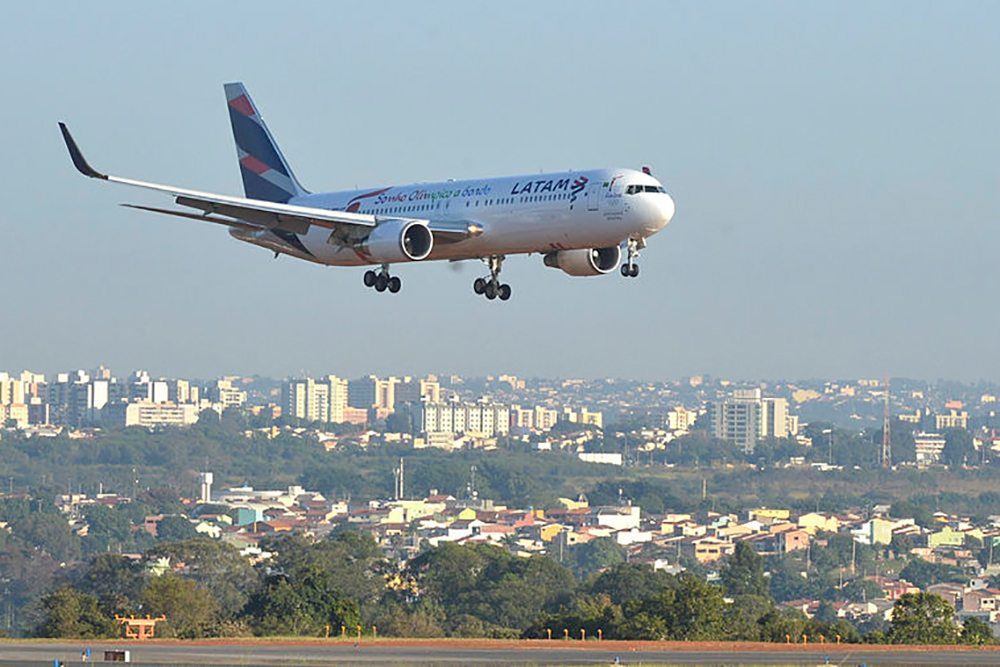 Aeronave da Latam em pleno voo, com pista de aeroporto abaixo