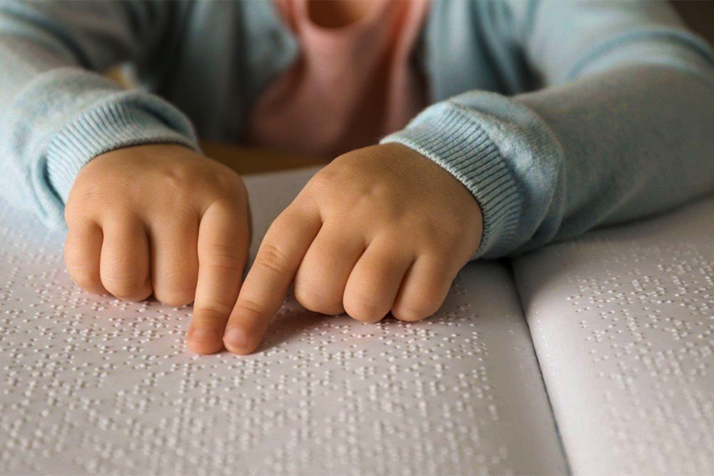 Criança lê texto em braile