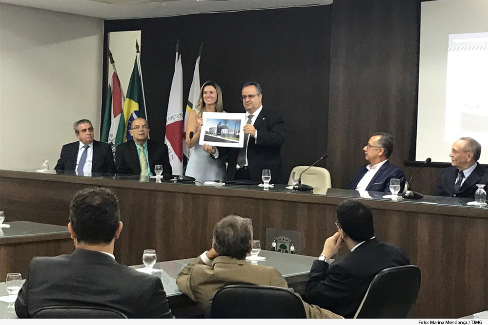 Foto mostra reunião de pessoas, duas na frente com foto na mão