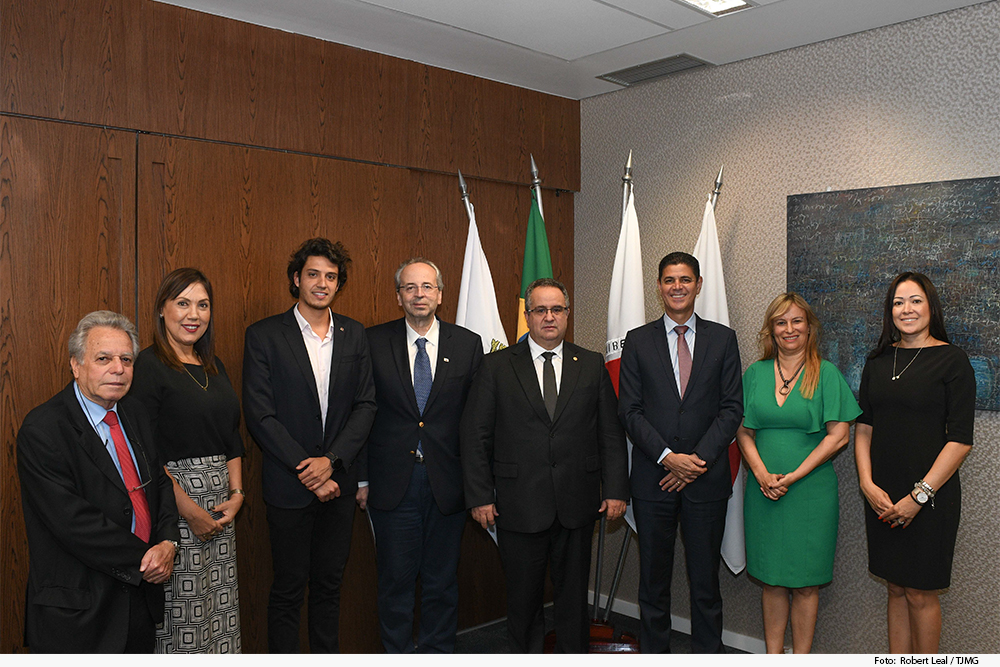 Autoridades, de pé, junto a bandeiras do Brasil e de MG