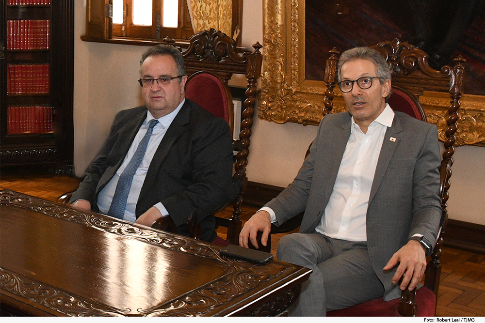 Magistrado e governador assentados em cadeira antiga em sala com livros