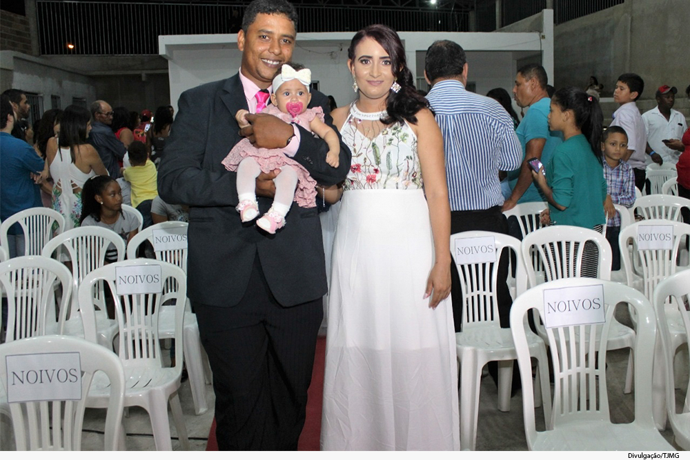 Homem e mulher, vestidos para o casamento, seguram bebê no colo