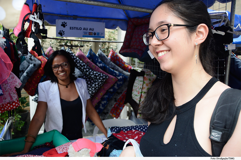 Duas mulheres sorrindo em barraca de roupas para pet