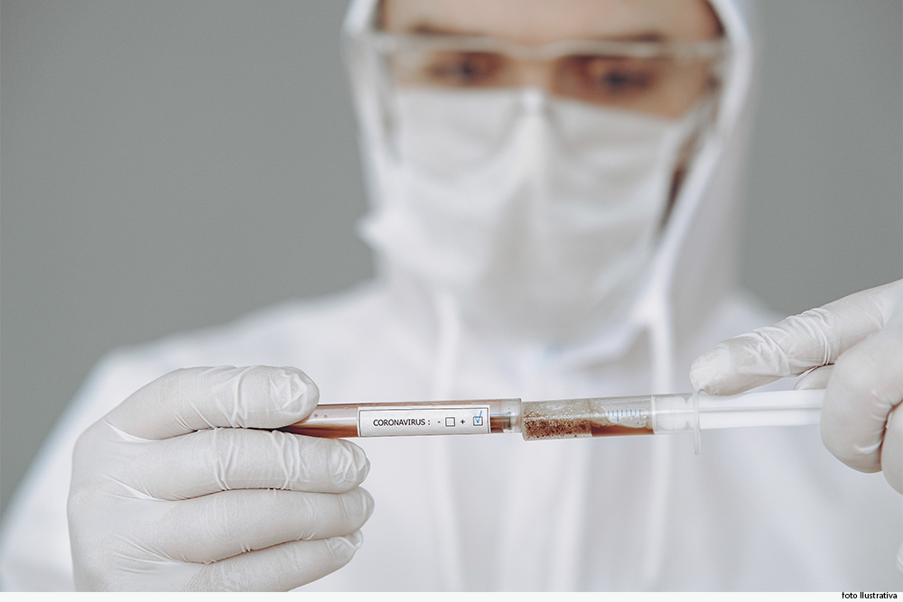 Técnico protegido por equipamentos de segurança pessoal examina sangue