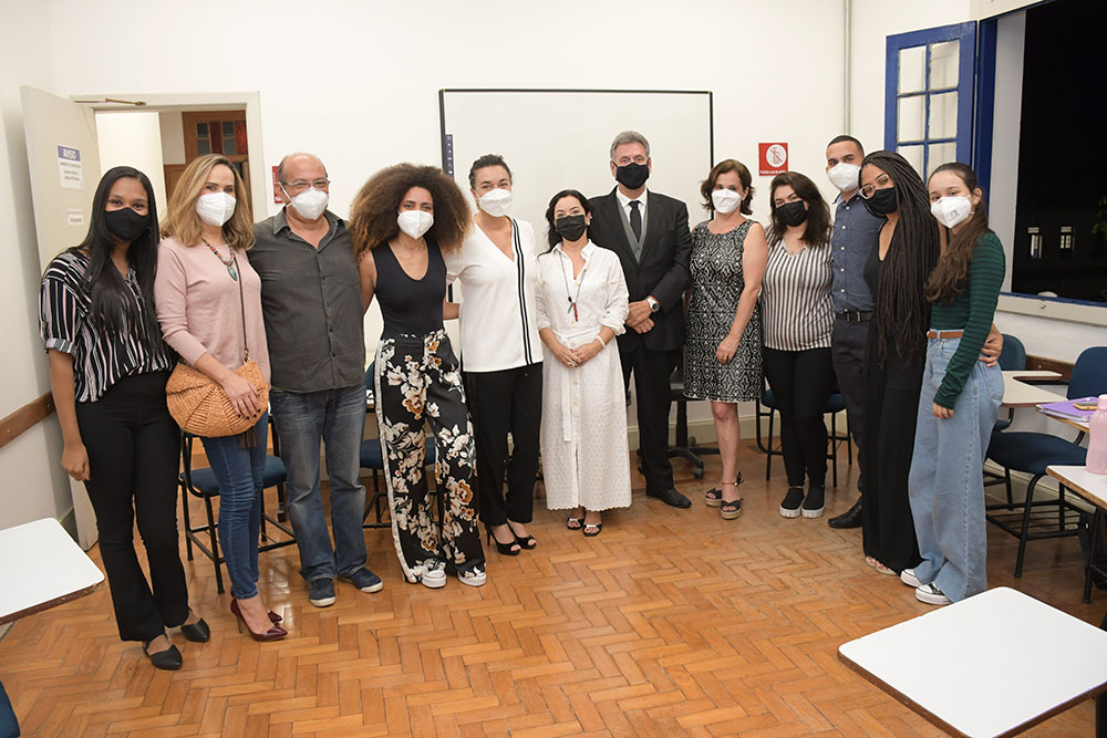 Participantes de projeto de pé, em sala na PUC Minas