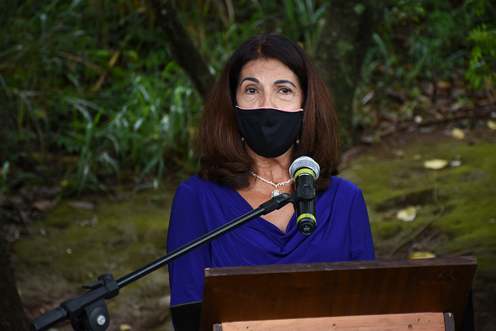 Magistrada, de máscara, discursa em evento