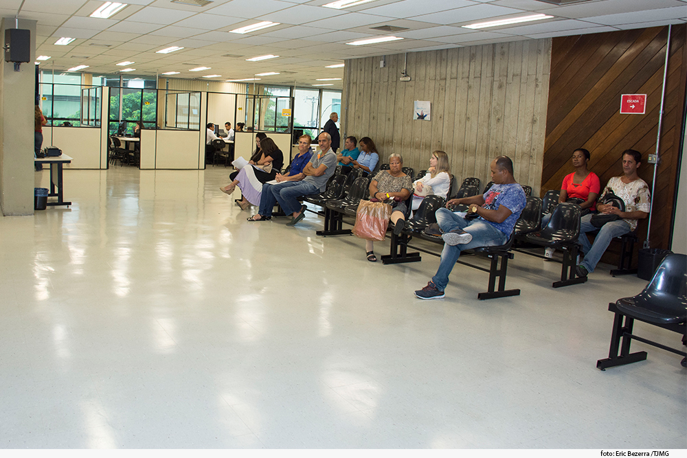 Foto mostra salão com várias pessoas sentadas