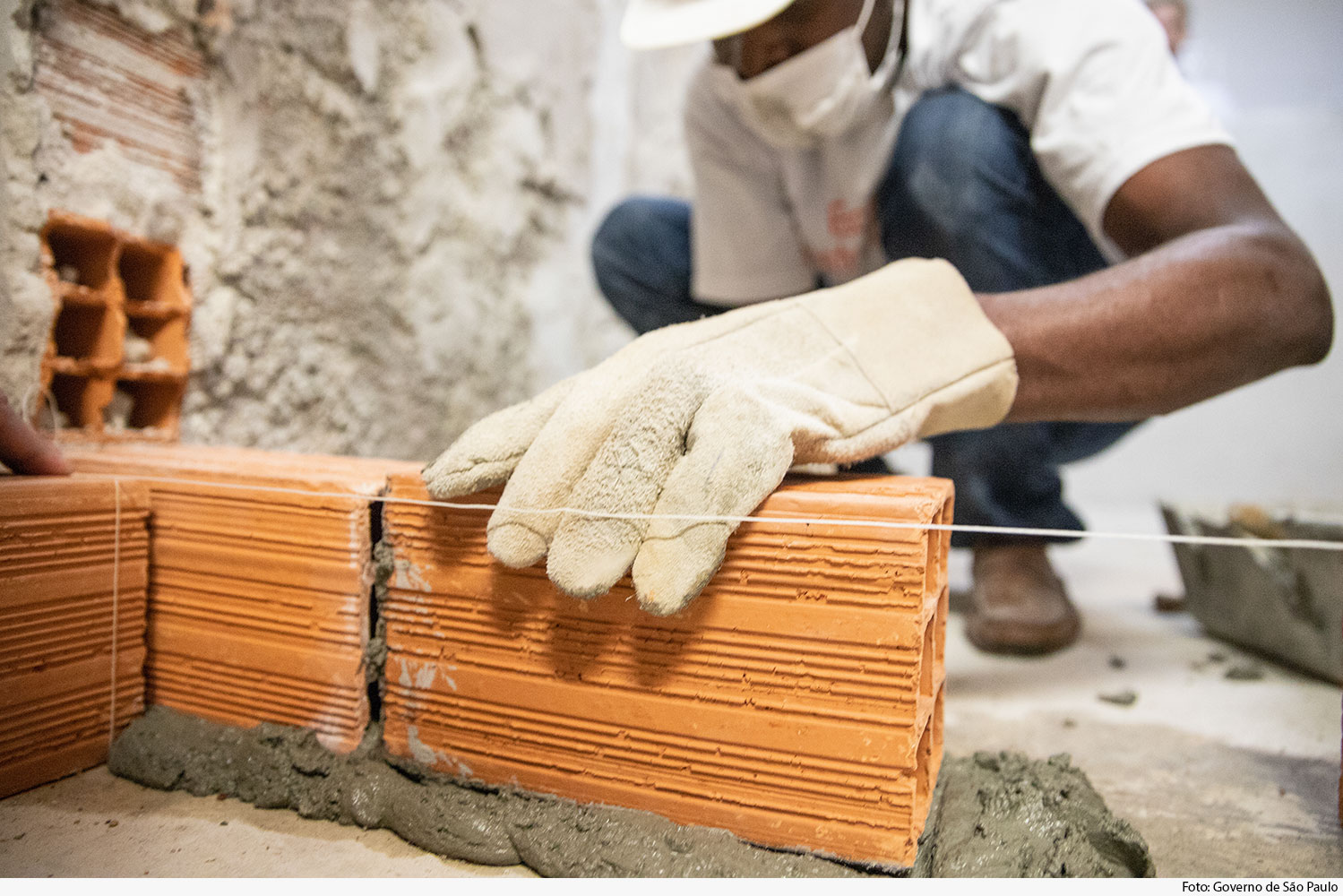 Mão de operário assentando tijolo sobre cimento