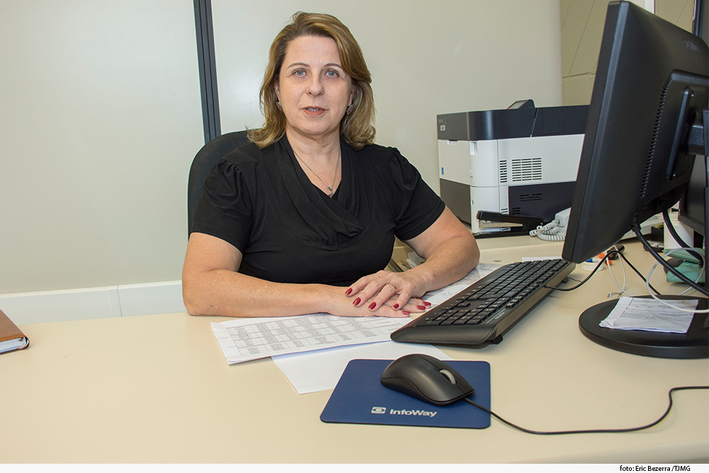 Foto mostra mulher de cabelos louros em frente a um computador