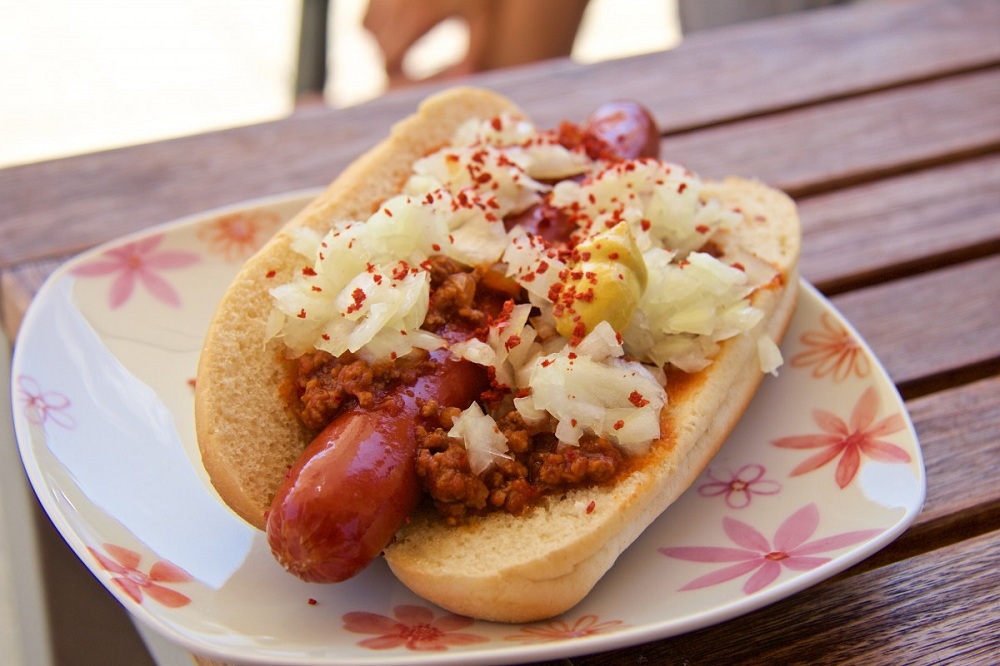 Cachorro-quente em prato sobre mesa de madeira