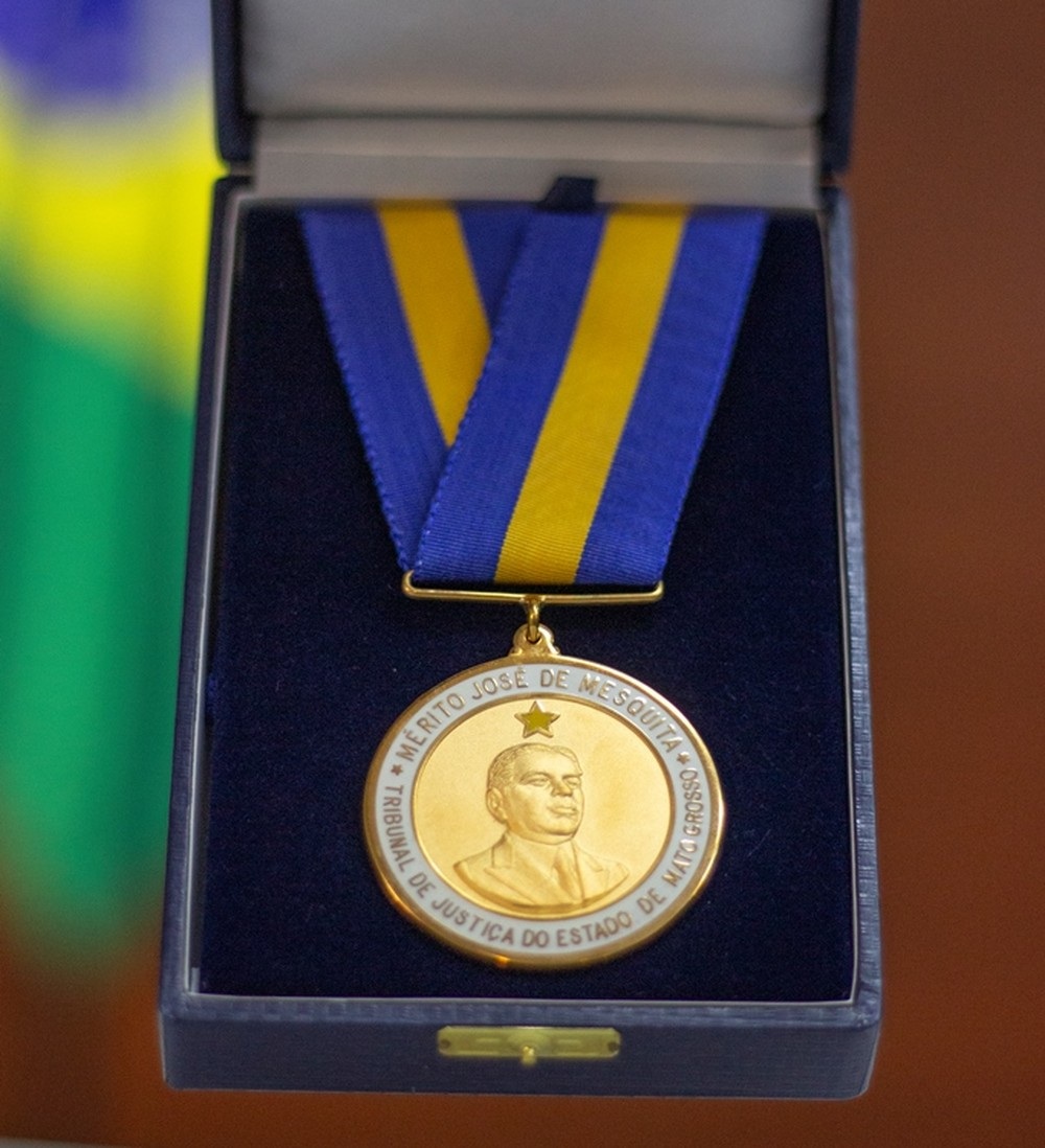 Medalha em estojo aveludado, tendo a bandeira nacional ao fundo