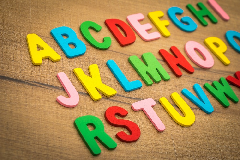 Letras coloridas do alfabeto, feitas de madeira, sobre mesa