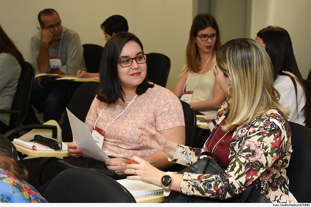 Participantes do curso, sentados, em sala de aula, interagem 