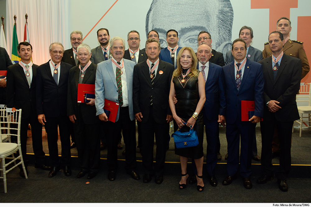 Homenageados com medalha diante de painel com imagem de JK