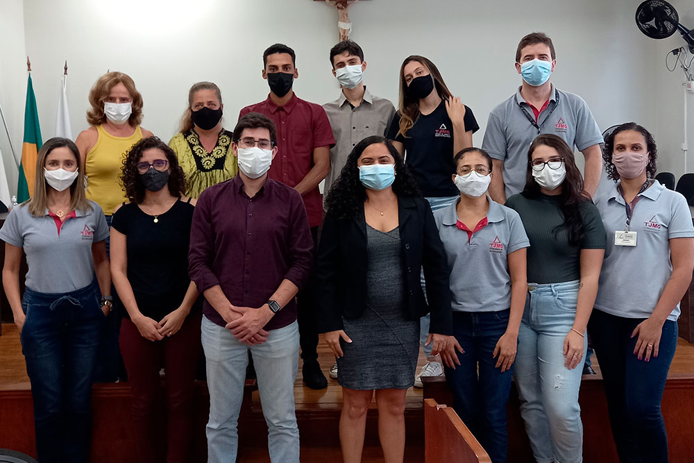Equipe no Salão do Júri da comarca, tendo crucifixo e bandeiras ao fundo