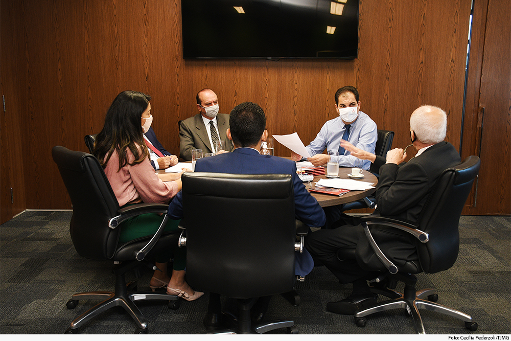 Mesa de reunião com cinco participantes, em gabinete