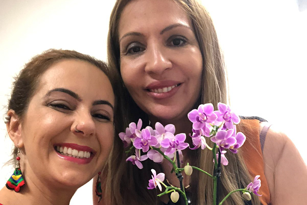 Mulheres lado a lado com orquídea na mão