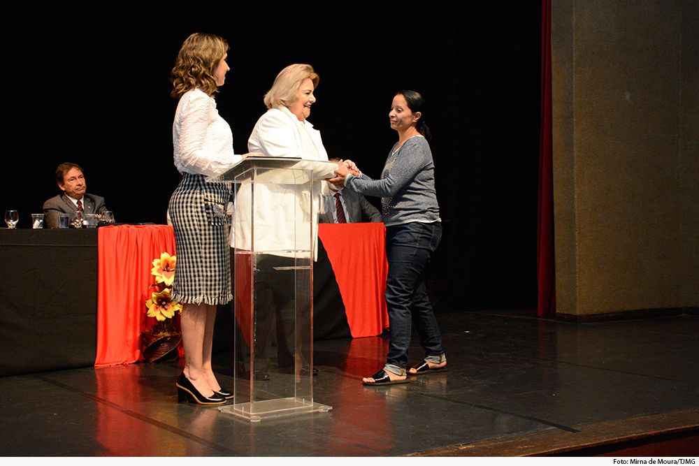 TRês mulheres no palco, com mesa de honra atrás