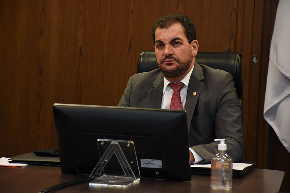 Presidente em sala de reunião acompanha atividades por teleconferência