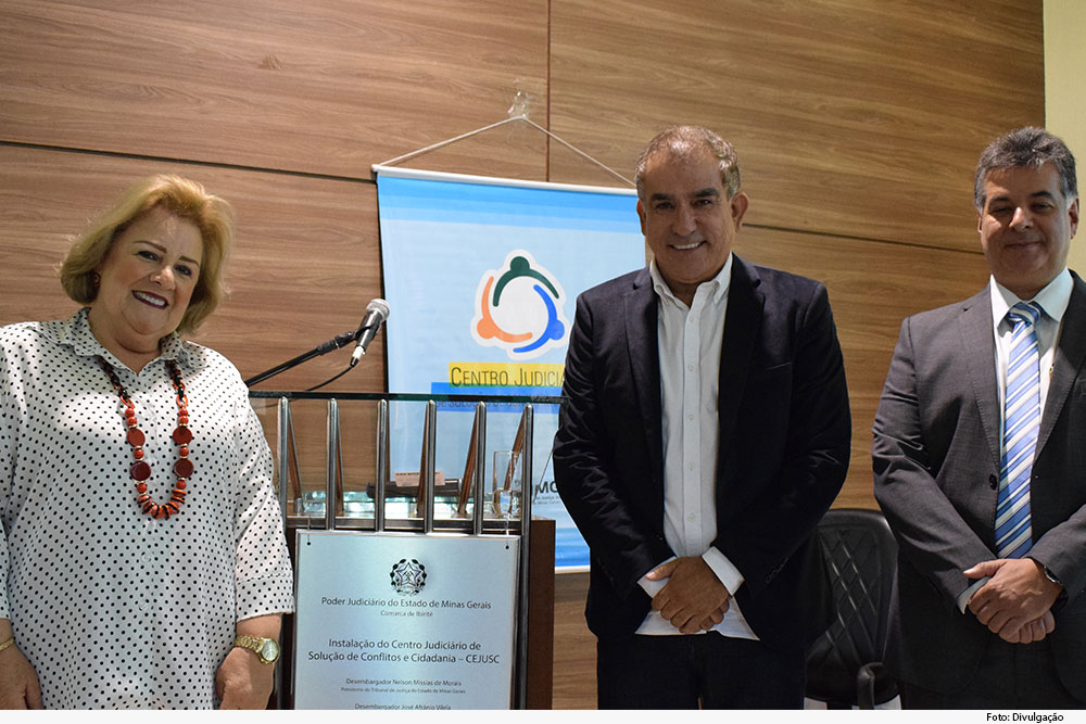 Uma mulher e dois homens e uma placa