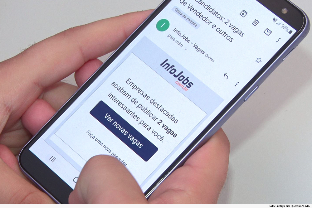 Mão segurando o celular com anúncio de vaga para emprego