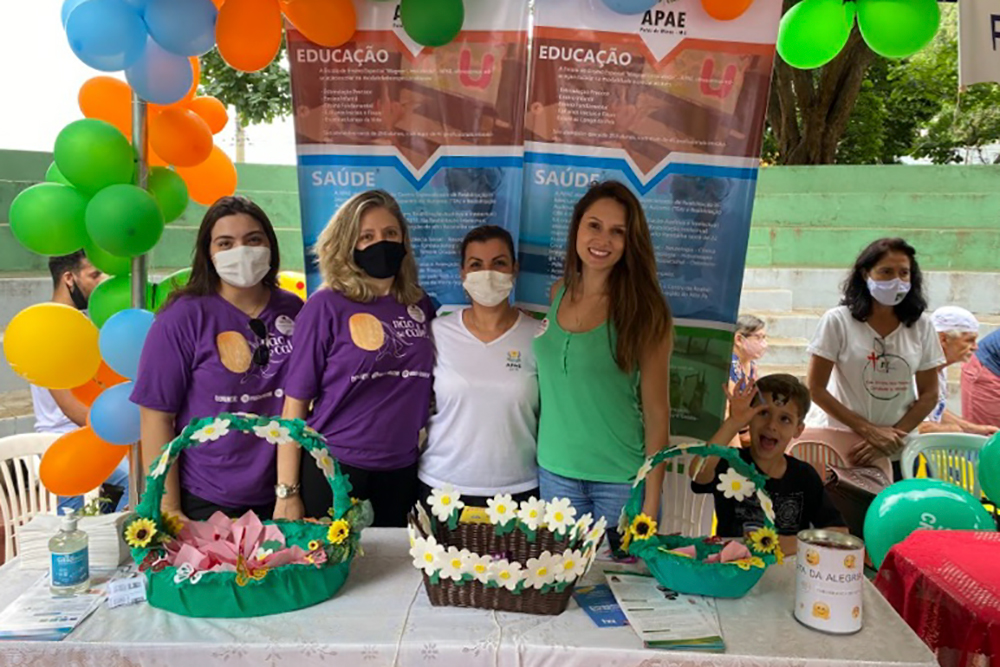 Juíza e equipe diante de mesa com brindes e folhetos