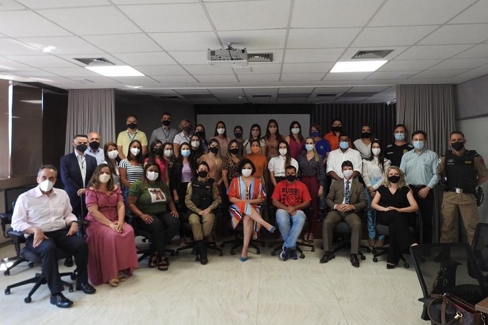 Grupo de pessoas de várias instituições, sentadas, em sala de reunião